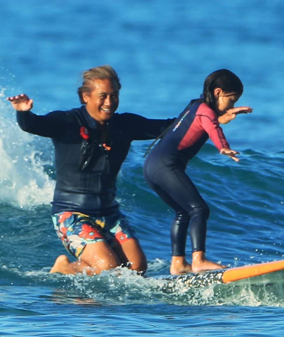Child learning to surf with an instructor helping her